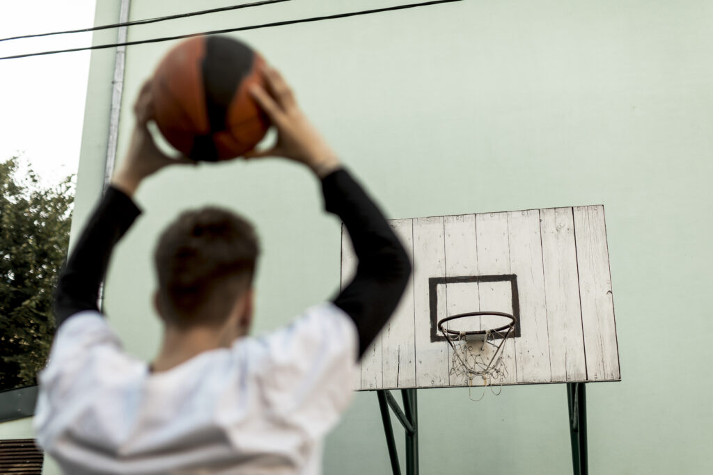 back view man throwing basketball