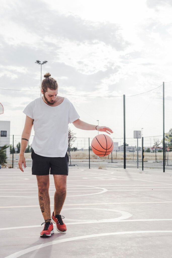 man dribbling basketball in the court